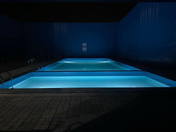 An Olympic-sized competitive swimming pool with blue lane markers and starting blocks.