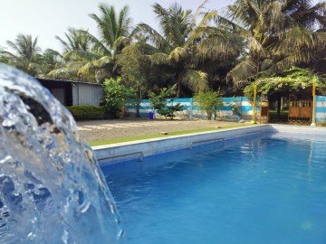 A stone waterfall cascading into a luxury backyard swimming pool.
